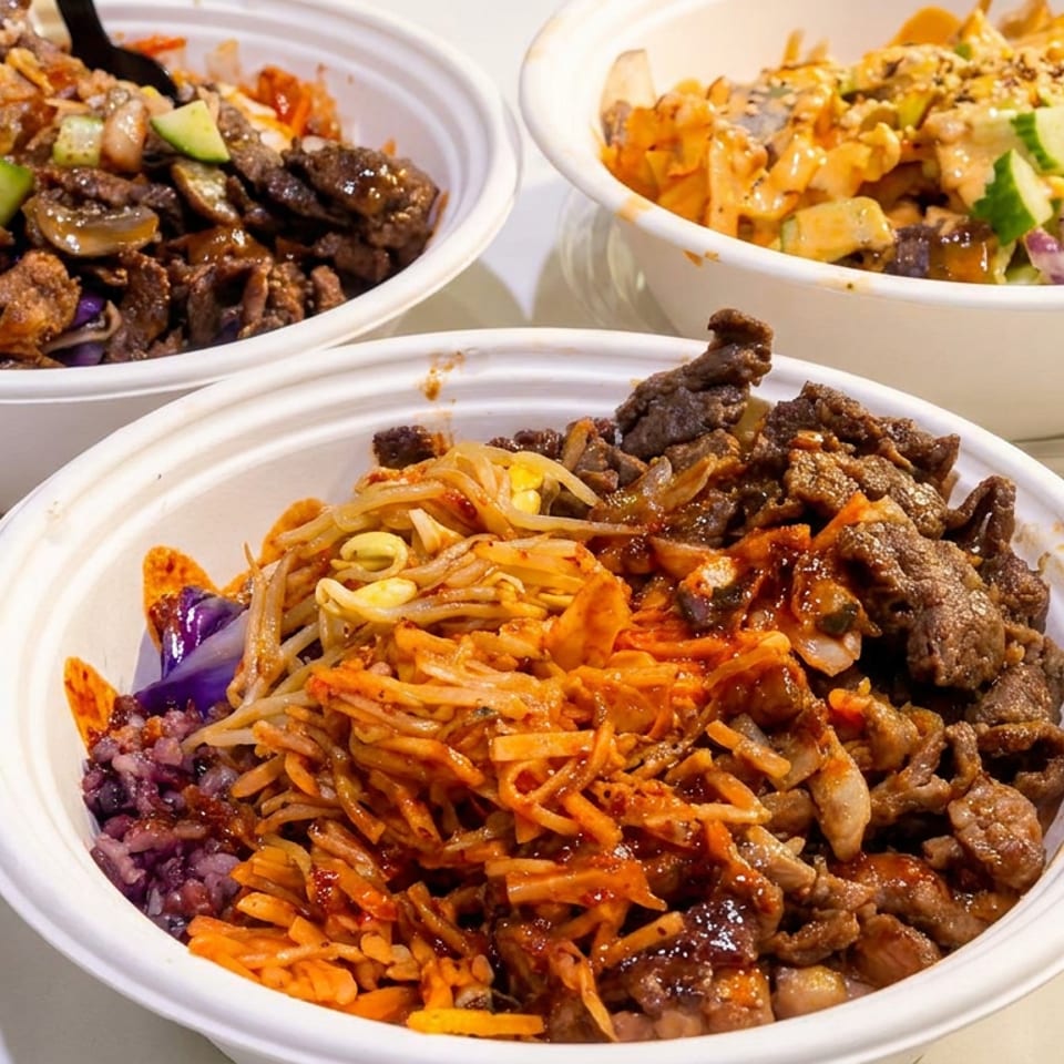 Three bowls of Korean BBQ, one with beef and bean sprouts, another with chicken and cucumbers.