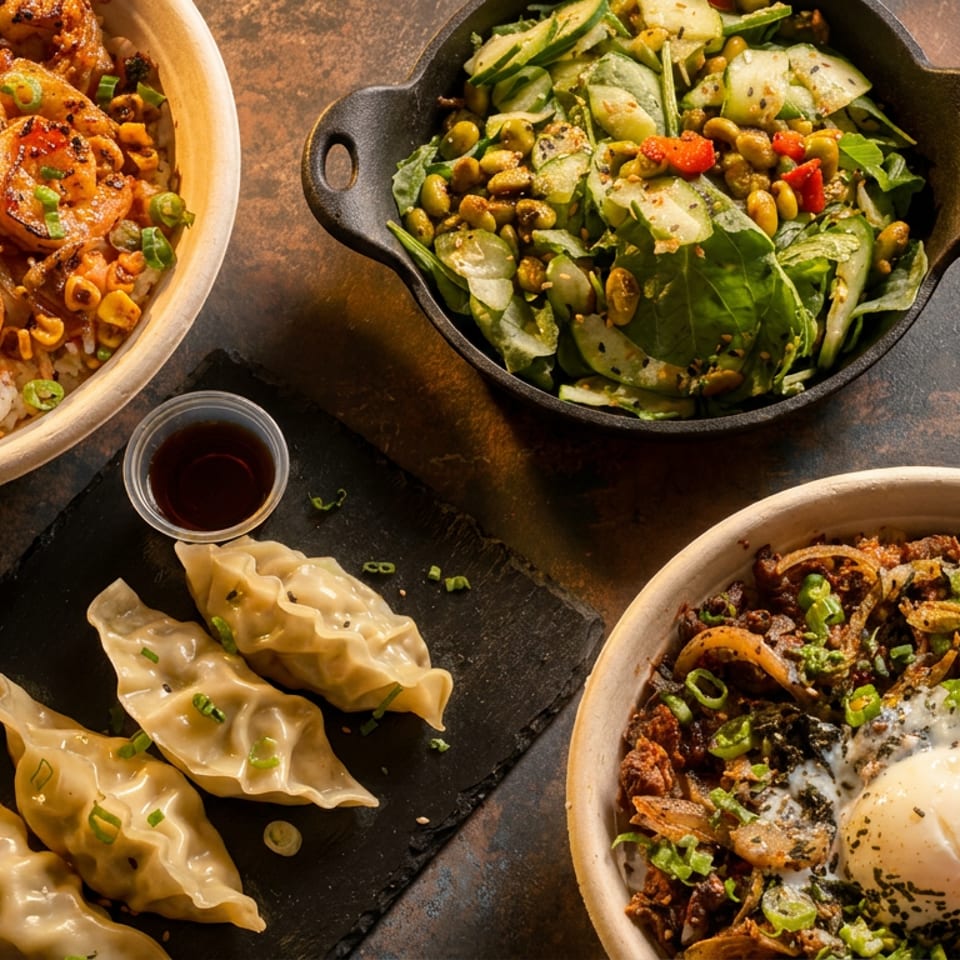 An overhead shot of various Asian dishes, including shrimp, dumplings, salad, and a rice bowl.